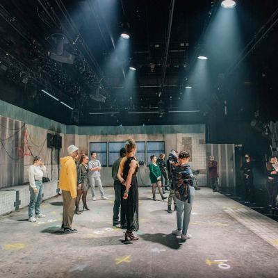 Actors on stage speaking to the director during a rehearsal